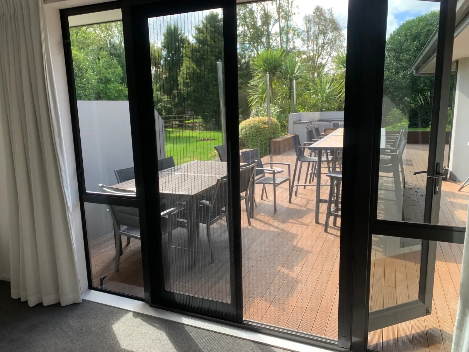 Brio folding screens across a slider to a deck with outdoor dining and rural Matamata views