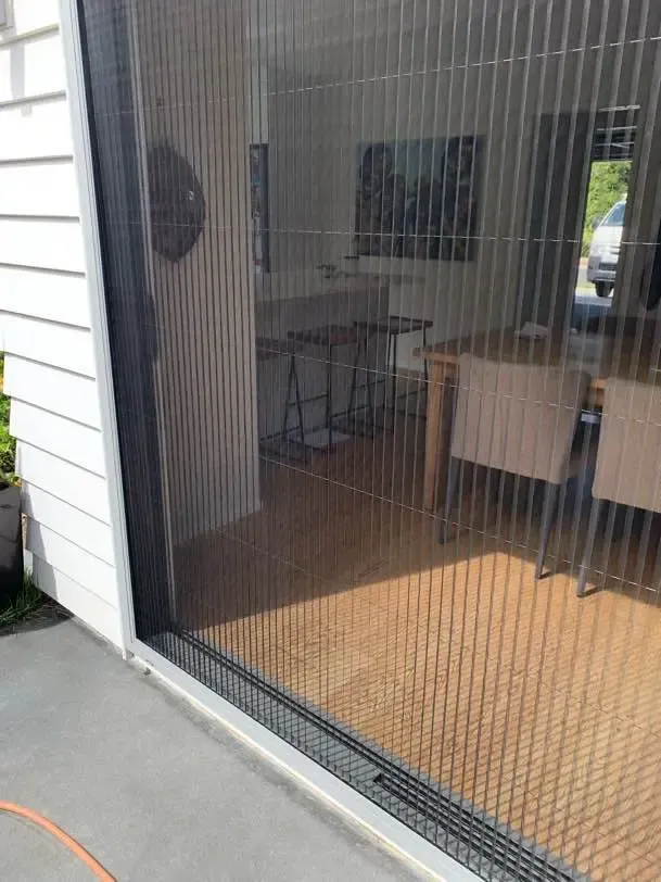 Brio pleated screen across a dining slider, table and kitchen visible through the mesh