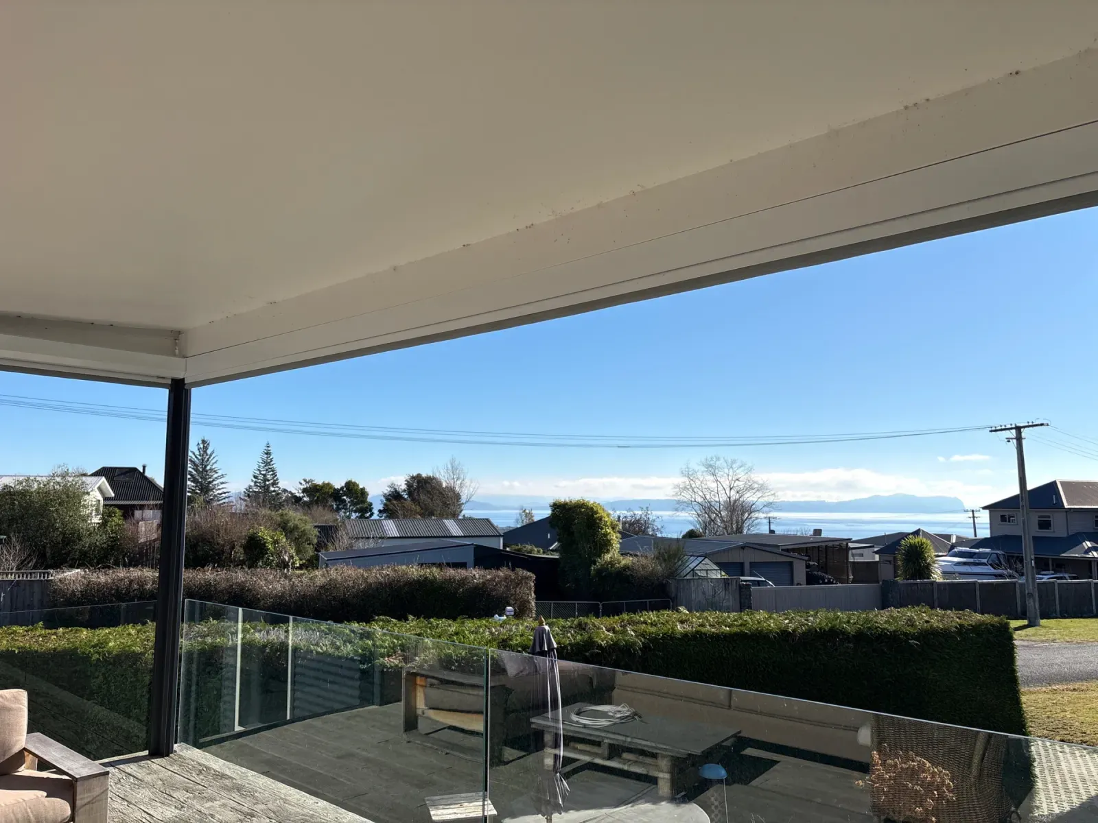 Executive motorised screen housing along the veranda beam of a covered lakefront deck at Lake Taupō, screens retracted for the view