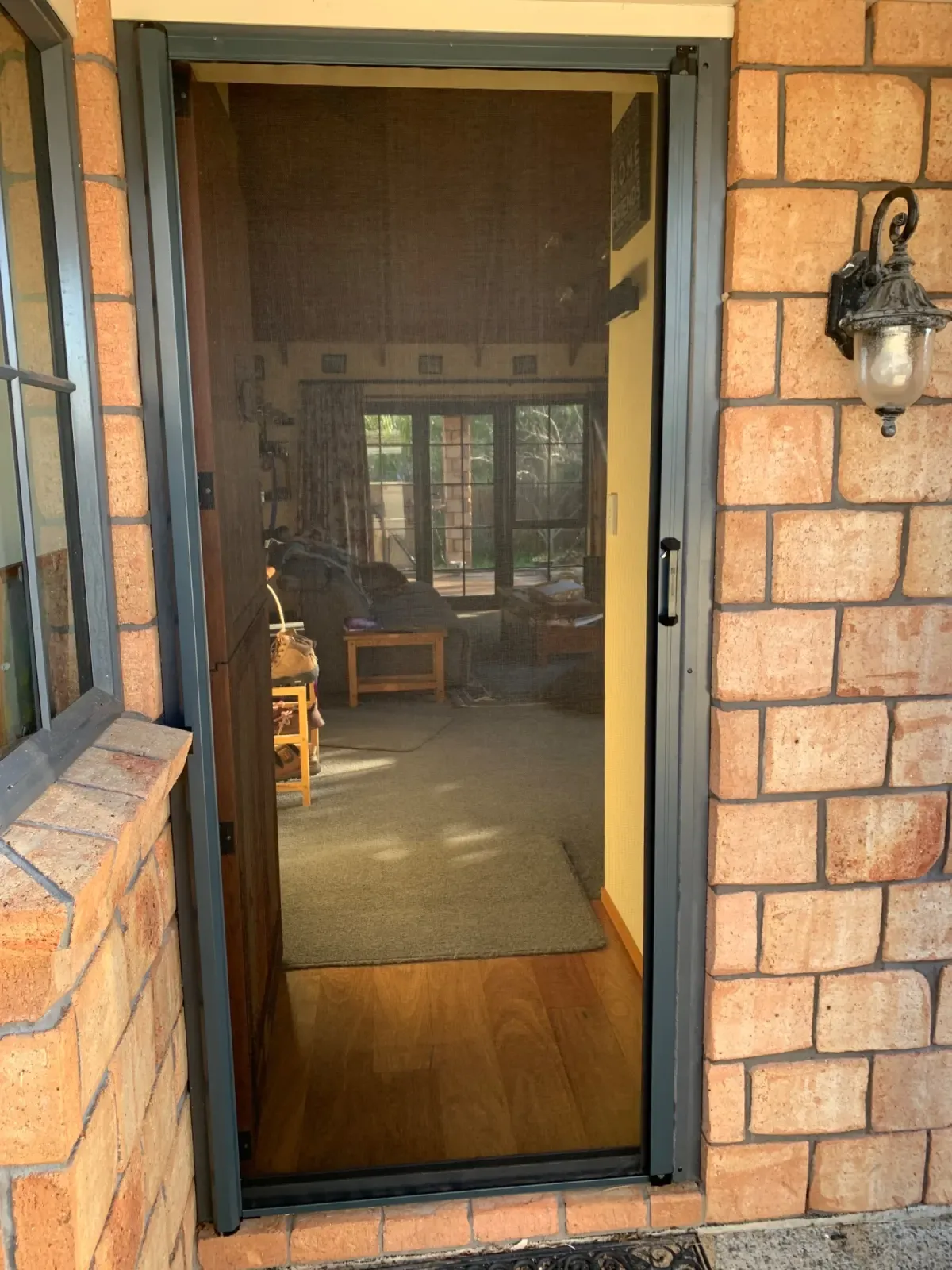 Grey Friars MeshLock screen door on a brick Hamilton home, opening to a warm interior