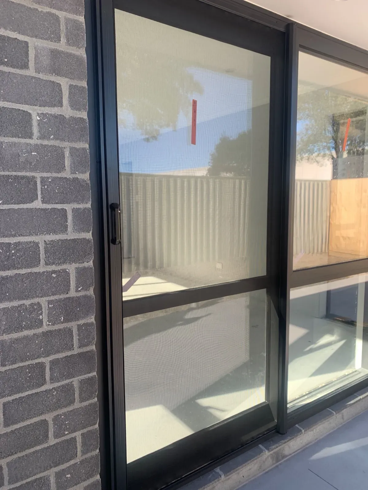 MeshLock retractable insect screen fitted to a ranch slider at a newly built Tauranga home, against finished brickwork