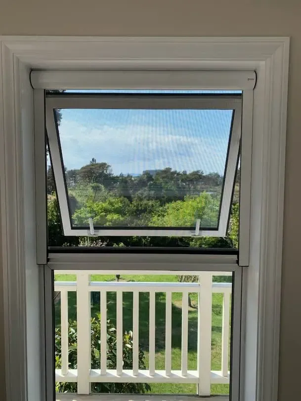 Serene screens on paired awning windows above a balcony rail, native bush beyond