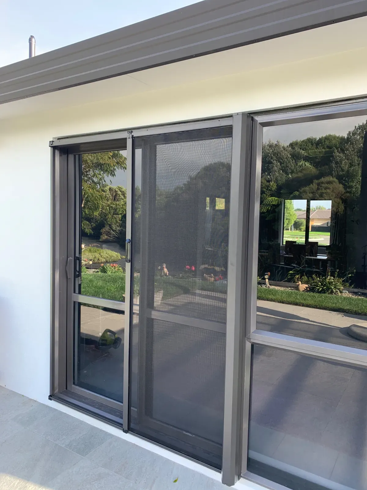 Retractable Wall Screen drawn across a family-room slider to a leafy Hamilton garden