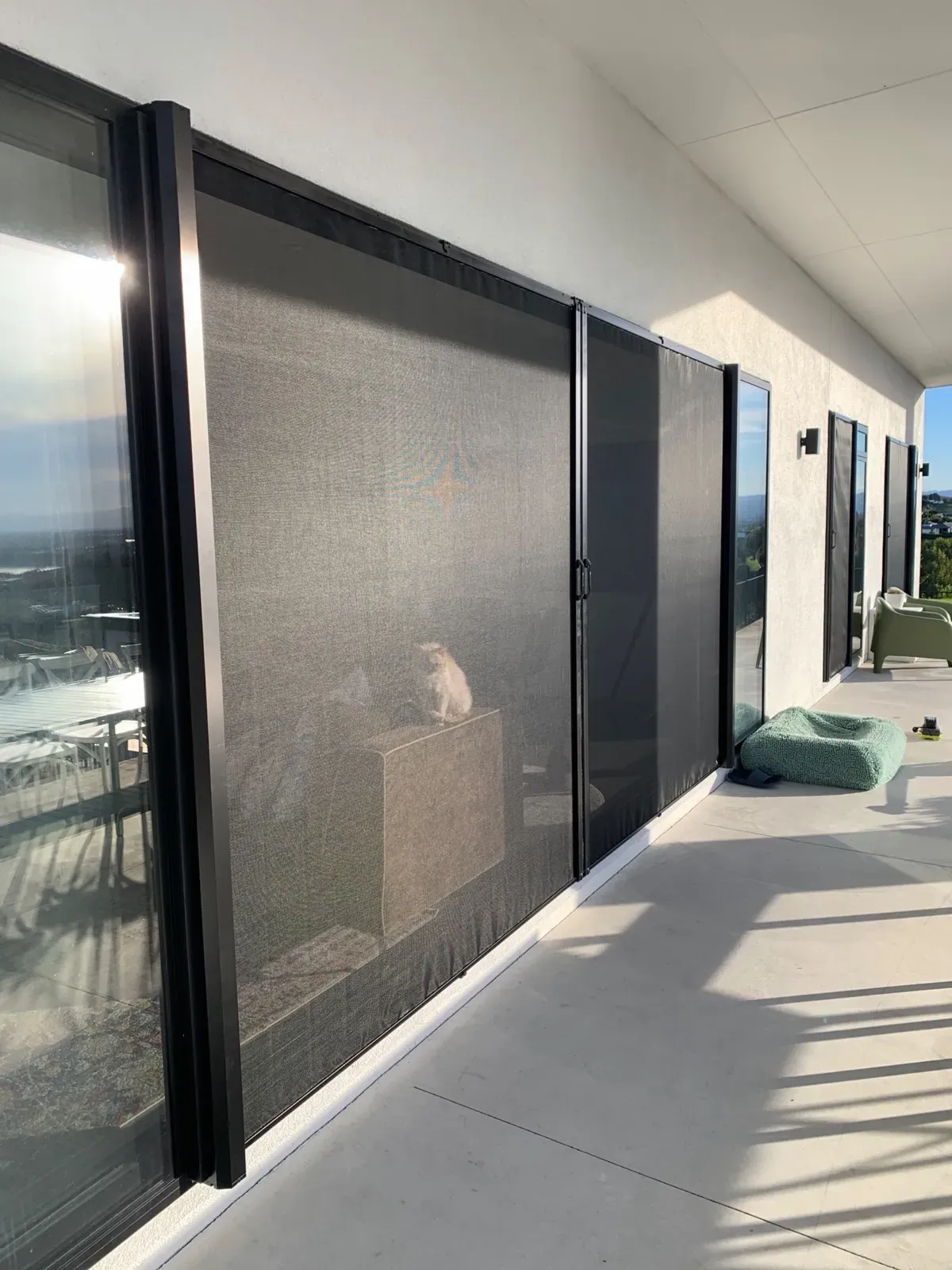 Retractable Wall Screens fitted across wide stacking patio doors on a modern home with a rural view