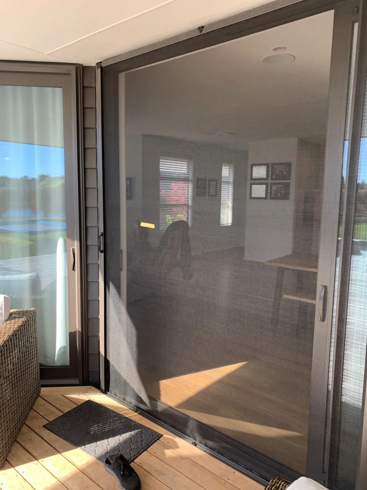 Retractable Wall Screen pulled across a wide stacker door, screening a dining area onto a timber deck