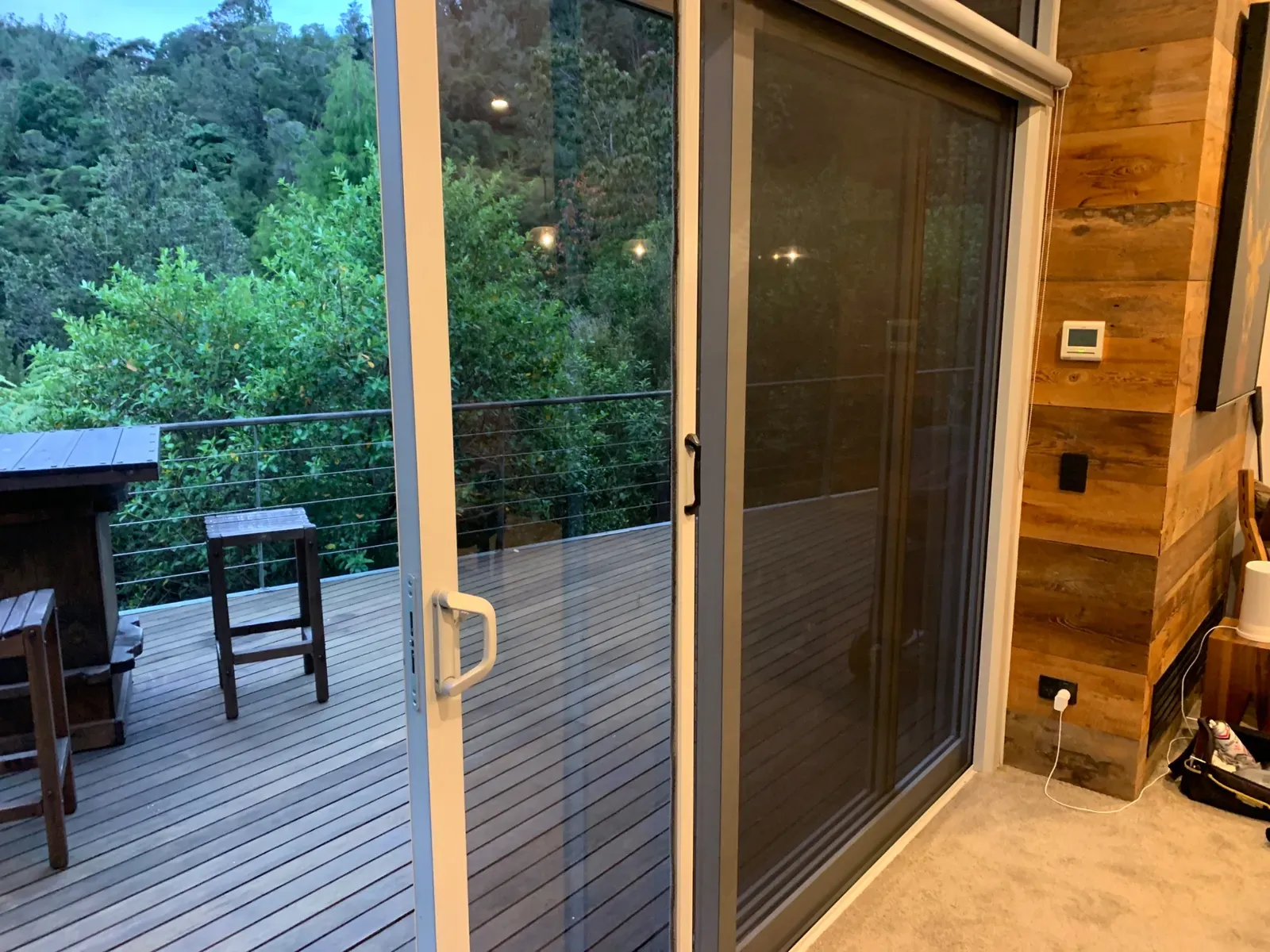 Silver Retractable Wall Screen on a dining slider, framing native bush from a Te Miro deck