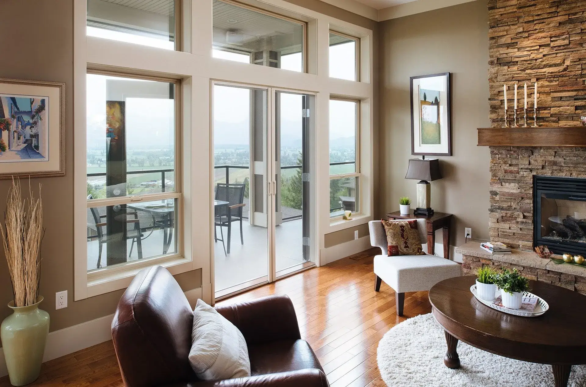 A retractable insect screen across French doors opening from a warm living room onto a deck with a rural outlook