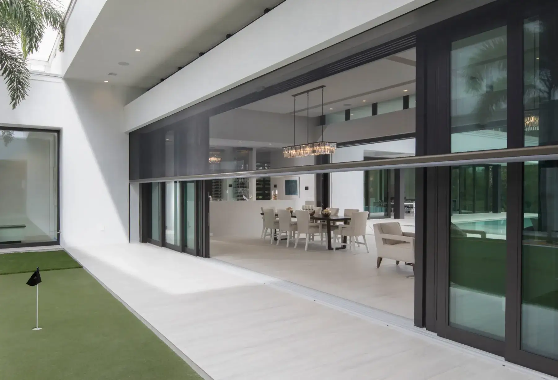 An open-plan living space opening to a deck through motorised outdoor screens