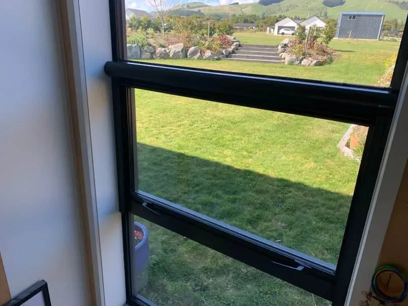 Black Serene screen and side tracks over an awning window framing a rural Waikato outlook
