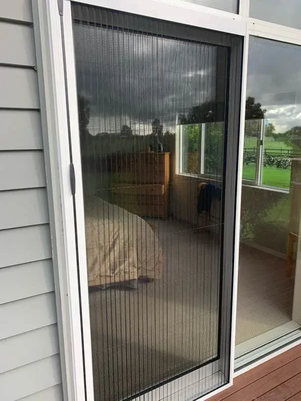Brio pleated screen drawn across a bedroom ranch slider on a grey weatherboard home