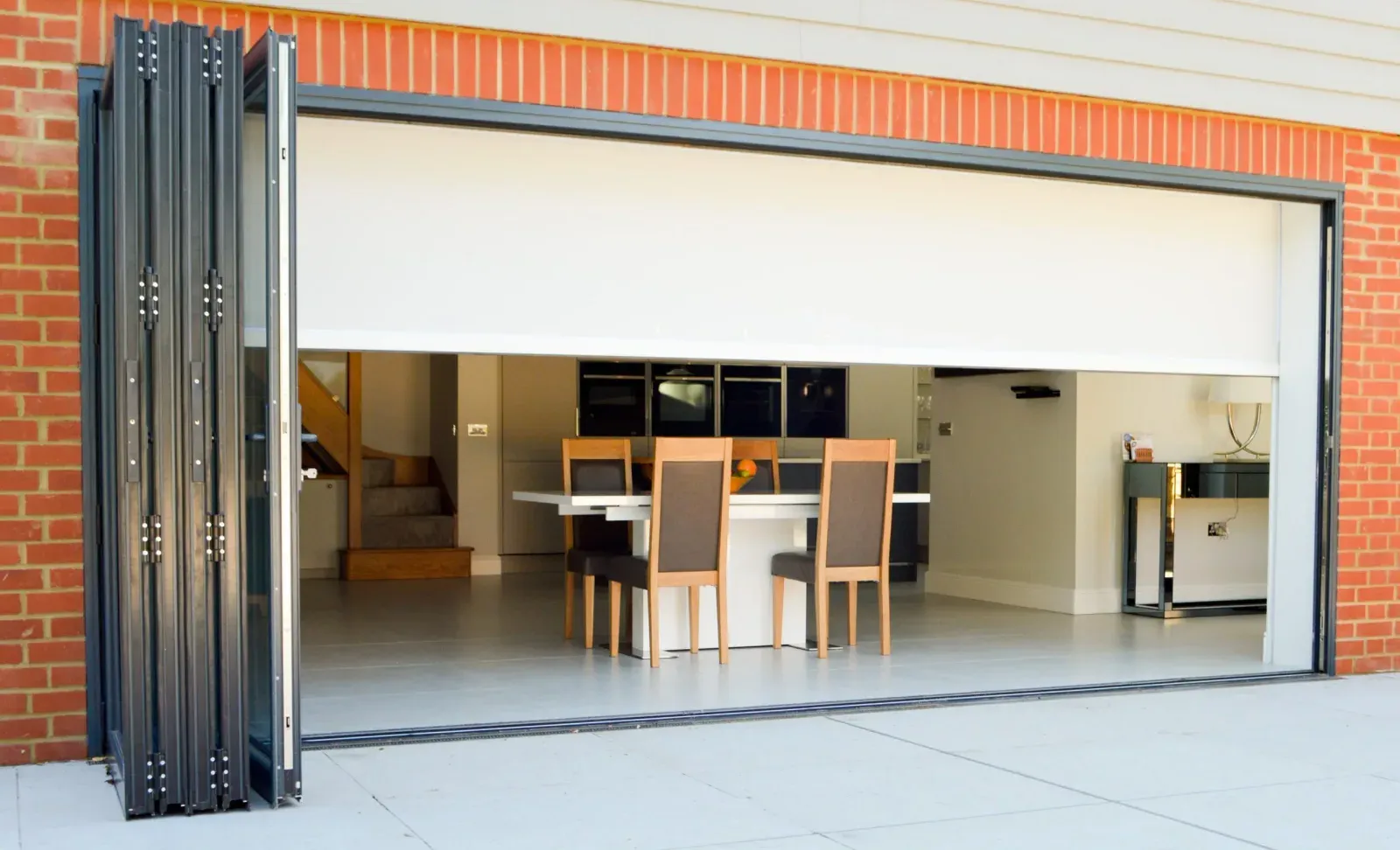White blockout fabric lowered over a wide bifold-door opening, screening the dining room behind