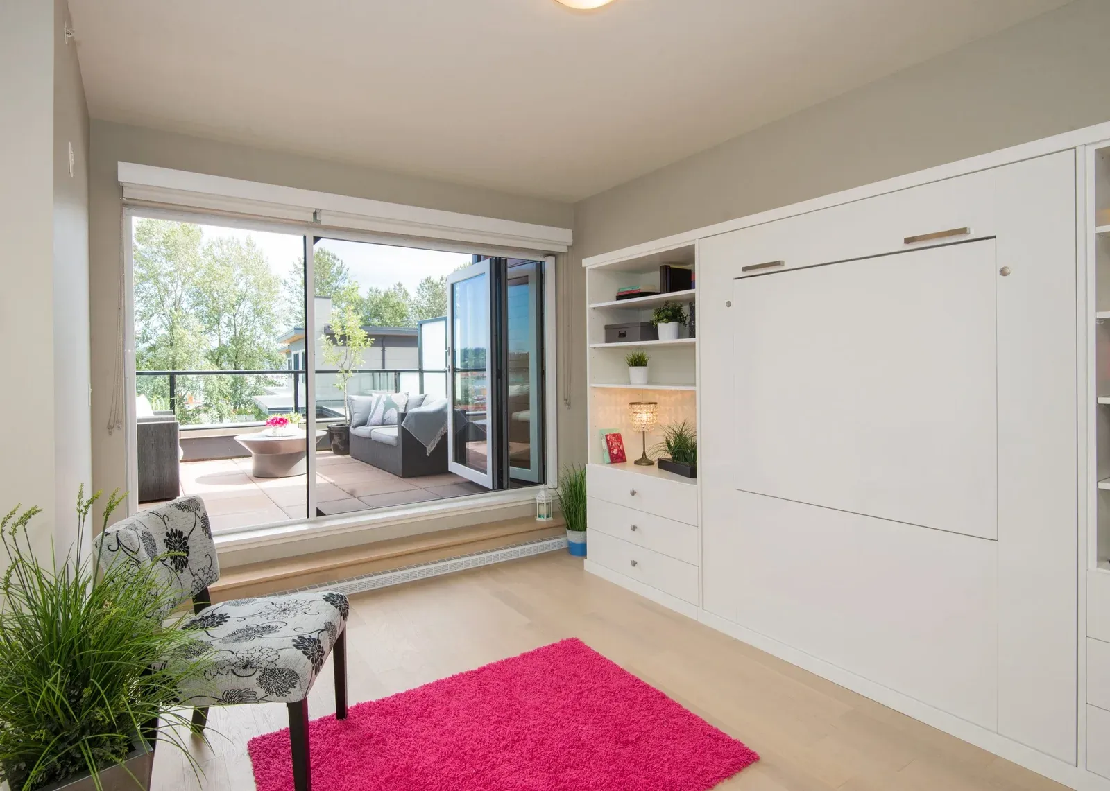 A retractable Wall Screen cassette mounted above wide glazed doors opening onto a furnished deck