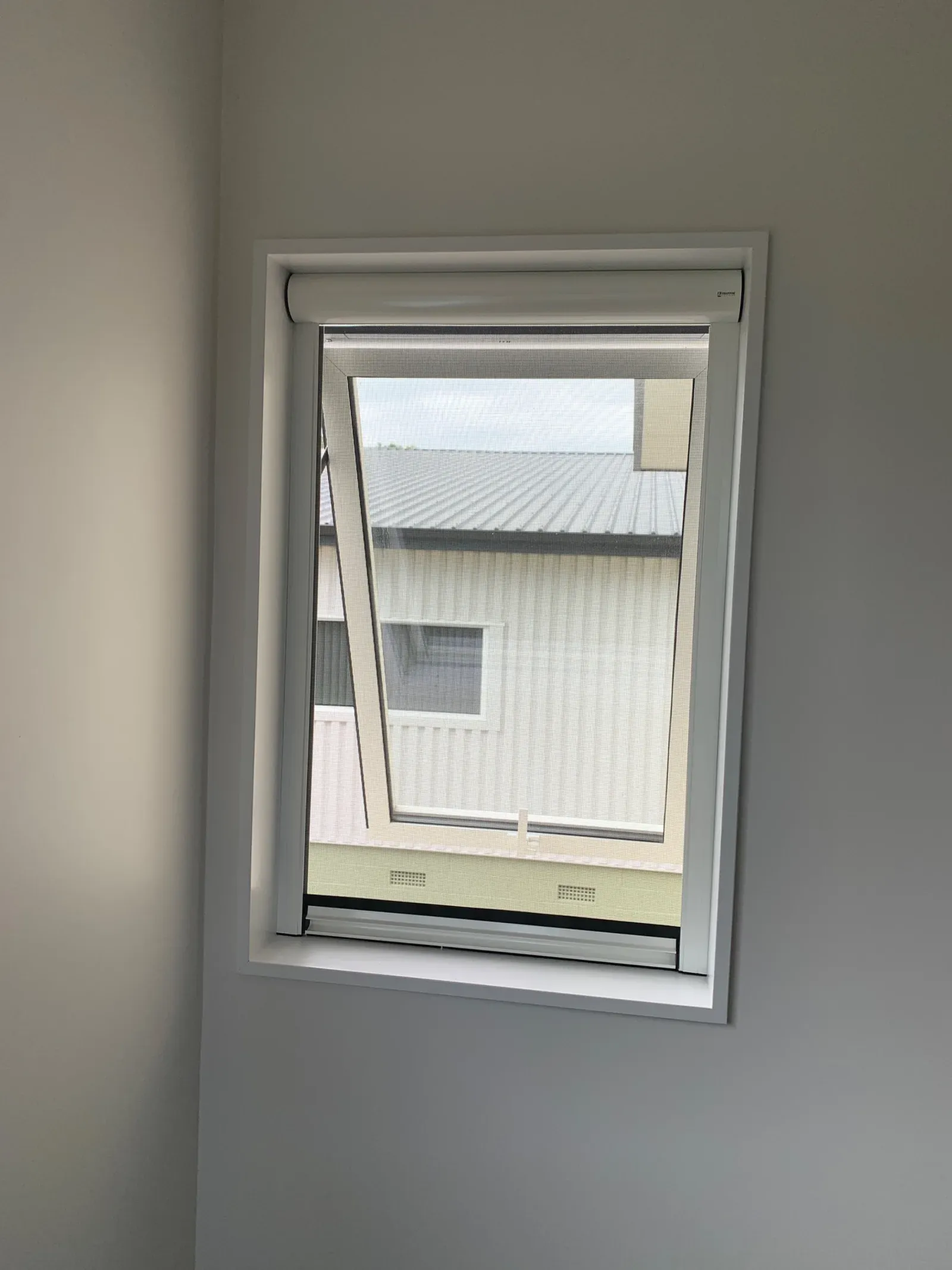 White Serene retractable insect screen drawn down inside an awning window, mesh retained in the side tracks