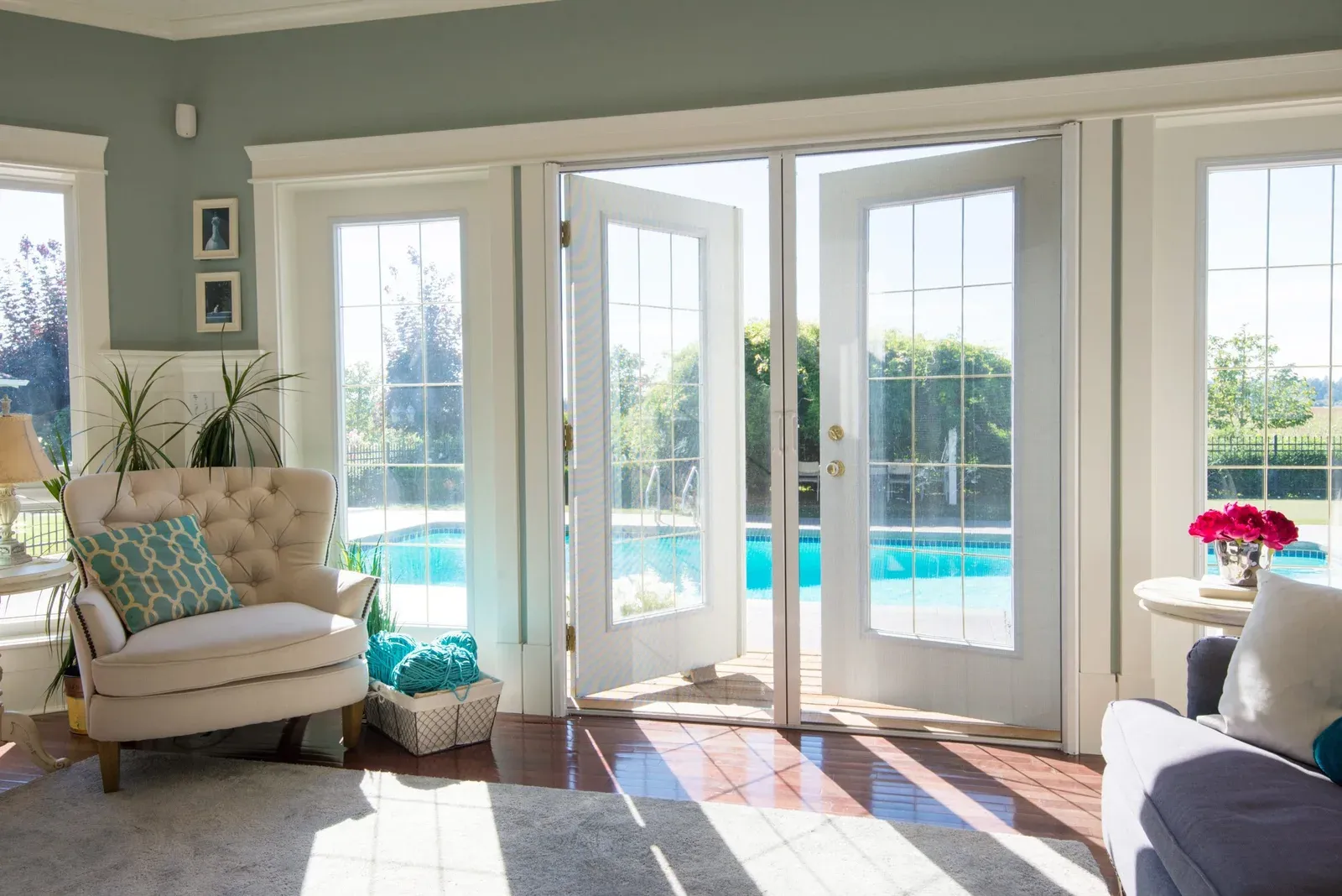 Retractable door screen deployed across white French doors opening onto a pool, seen from a bright living room