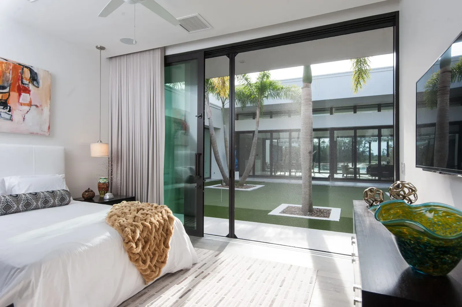 A retractable insect screen drawn across a wide sliding glass door opening onto a planted courtyard