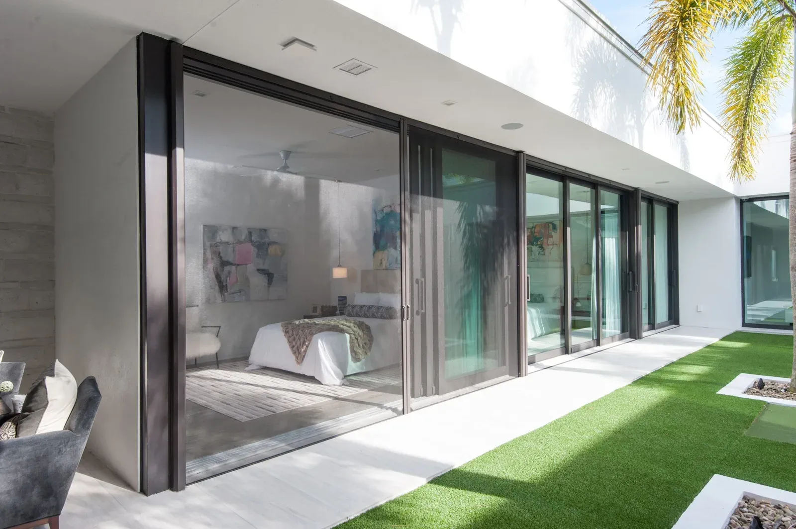 Retractable insect screen drawn across a modern sliding glass door onto a courtyard, bedroom visible through the mesh