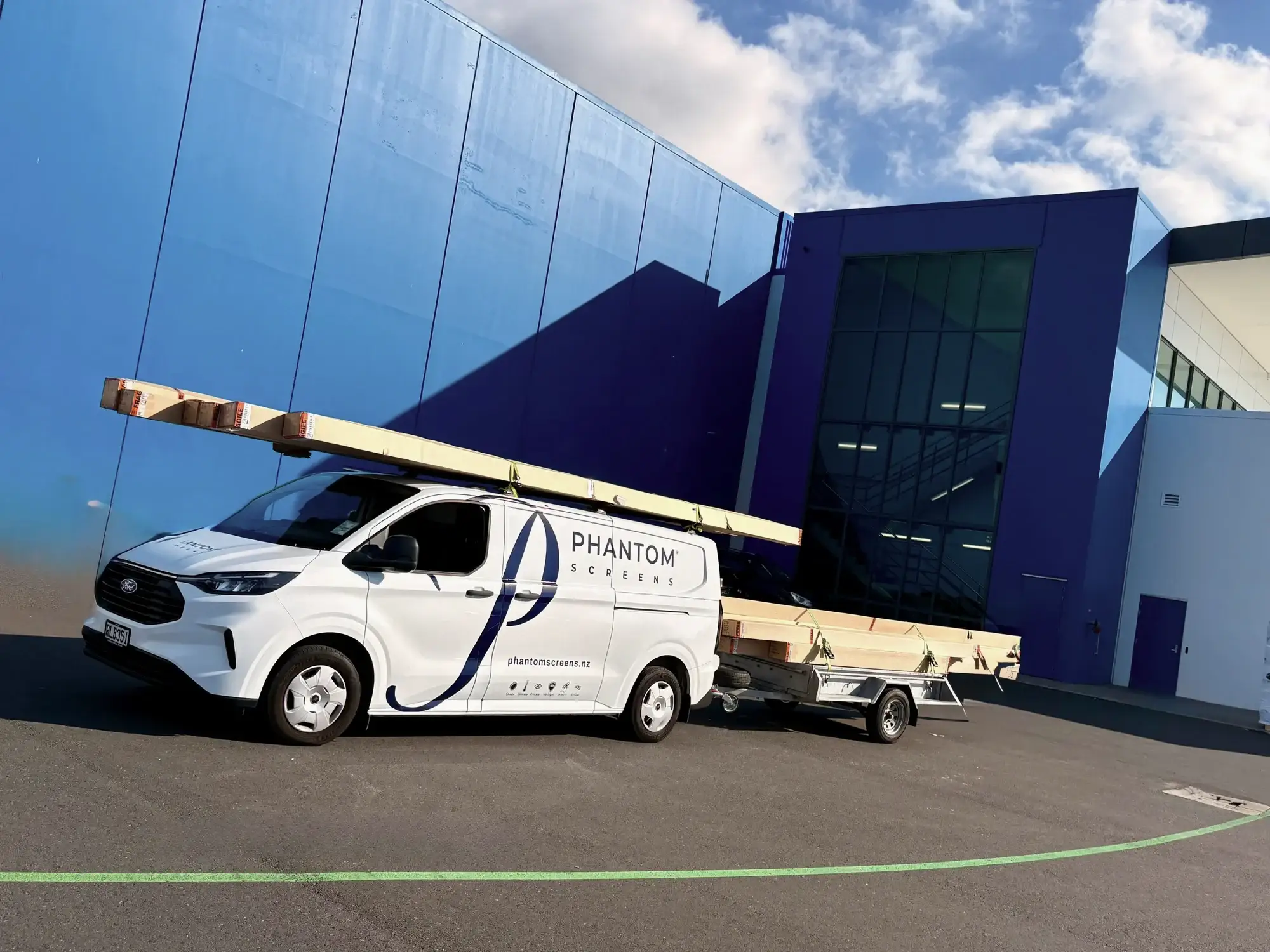 A Phantom Screens work van and trailer loaded with lengths of material, ready to head out for install work