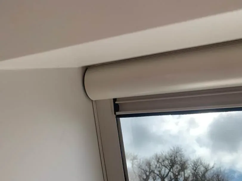 White Serene cassette fitted at the head of a sloping skylight window under a raked ceiling