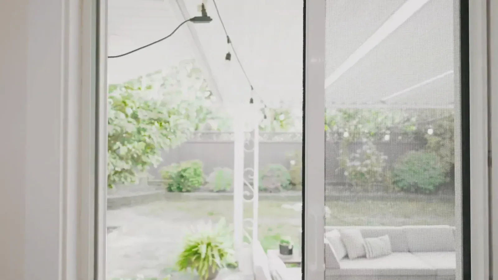 Captured edge door screen closed across a single patio door, with the garden visible through the mesh