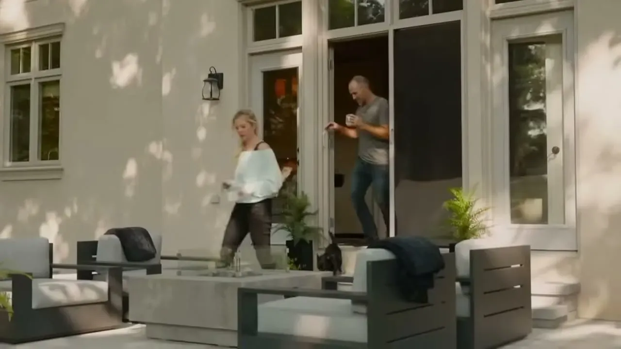 A family stepping onto a patio through open doors fitted with a retractable insect screen, the cat staying inside