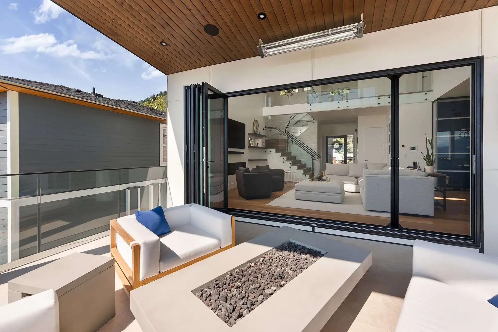Phantom retractable Wall Screen across wide bifold doors onto a deck, looking into a modern open-plan living room